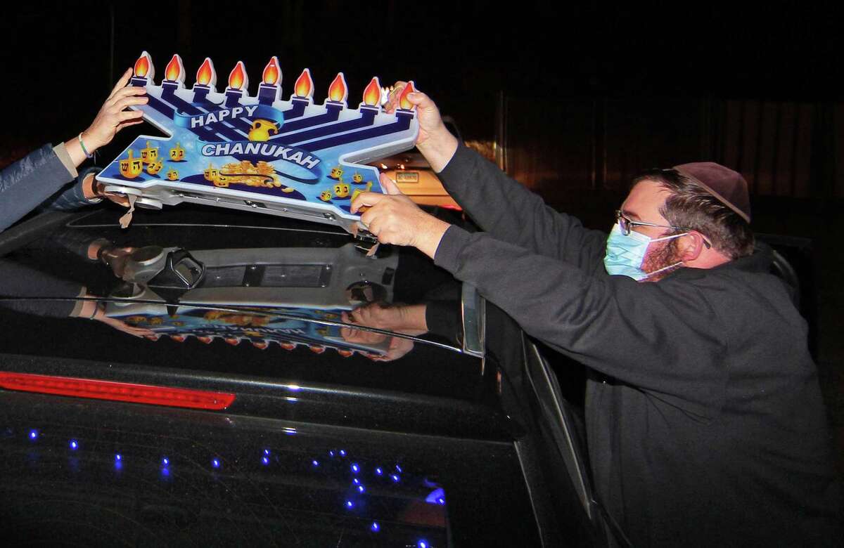 Chabad of Fairfield Rabbi Shlame Landa places a magnetic light atop a vehicle before the start of a Car Menorah Parade in Fairfield, Conn., on Thursday Dec. 10, 2020. A Menorah lighting to celebrate Hanukkah came at the end of the parade that started at Chabad of Fairfield, joined Chabad of Shelton and Chabad of Westport members midway along the route along Post Road in Fairfield.