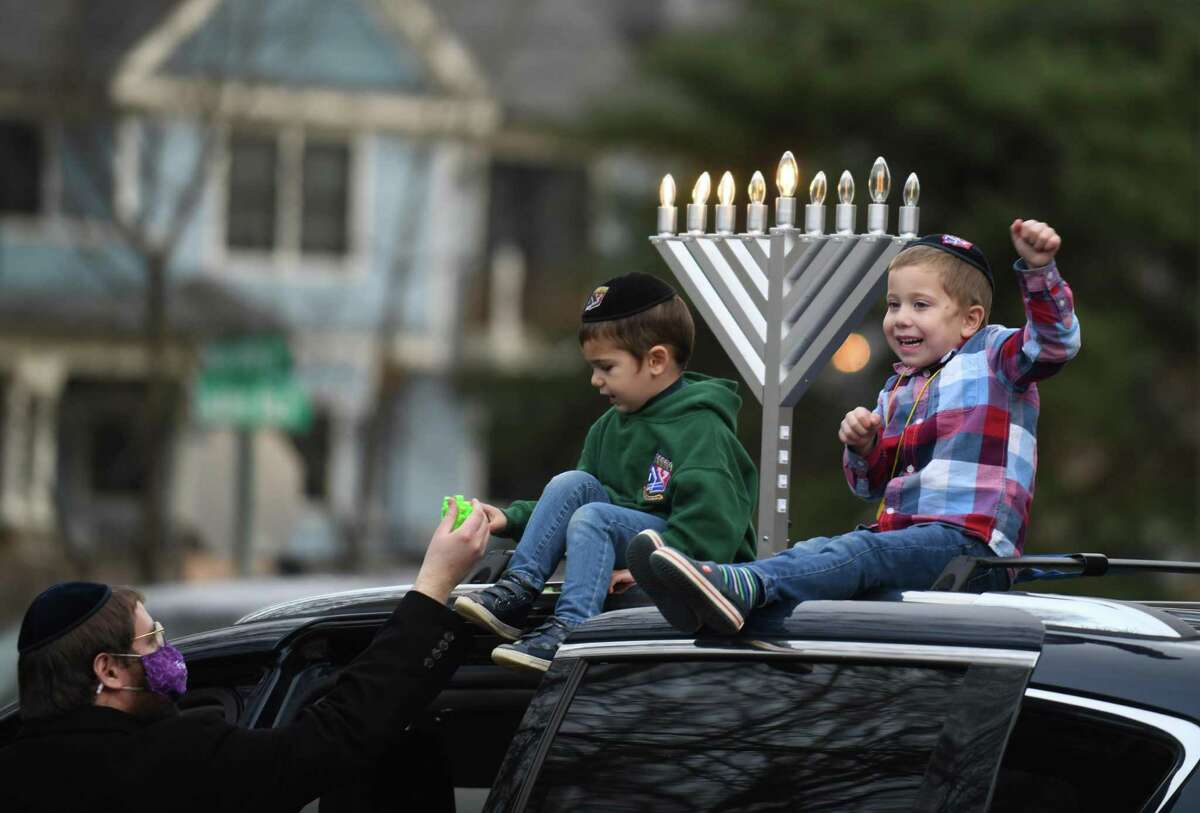 Above, Yossi Kamman and his children Levi, 3, and Mendel, 5, prepare for the at Perrot Memorial Library in Old Greenwich, Conn. Sunday, Dec. 13, 2020. Participants assembled at the library and were escorted through Greenwich to the Chabad giant menorah on Greenwich Avenue.