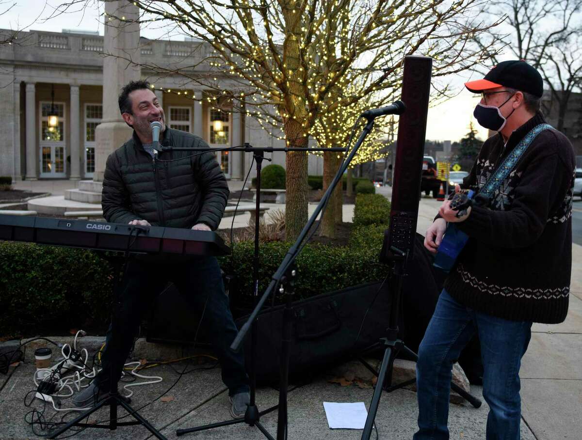 Jonathan Carr, left, and Bobby Doowah perform Hanukkah songs at the Chabad giant menorah in Greenwich, Conn. Sunday, Dec. 13, 2020. Folks celebrated Hanukkah by having a car parader through Greenwich to the Chabad giant menorah on Greenwich Avenue.