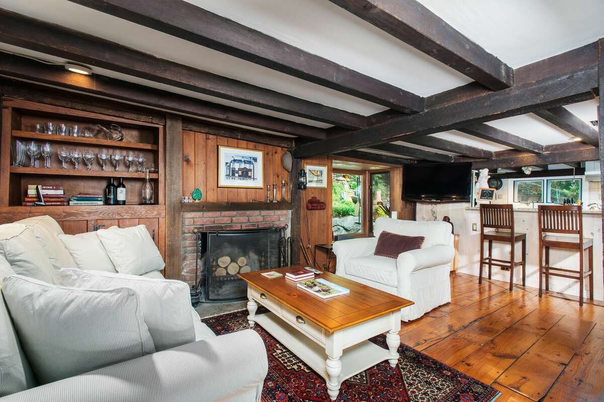 Living room with fireplace, exposed beams and wide-planks floor at 28 Valley Road, Westport. Period details -- including well-maintained, wide-planked pine wood floors and exposed beams -- blend well with modern features, such as the new windows and all new baths with heated floors. The interior was freshly painted.