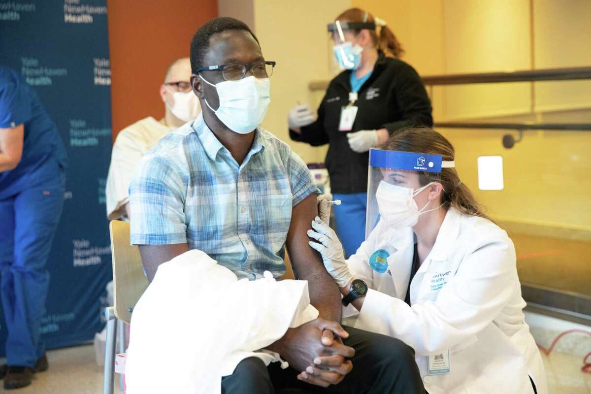 Onyema Ogbuagu, an infectious diseases specialist for Yale New Haven Health and principal investigator at the Yale Center for Clinical Investigation for the Pfizer-BioNTech COVID-19 vaccine trial, receives his vaccination from pharmacist Natasha Stroedecke Tuesday, Dec. 15, 2020.