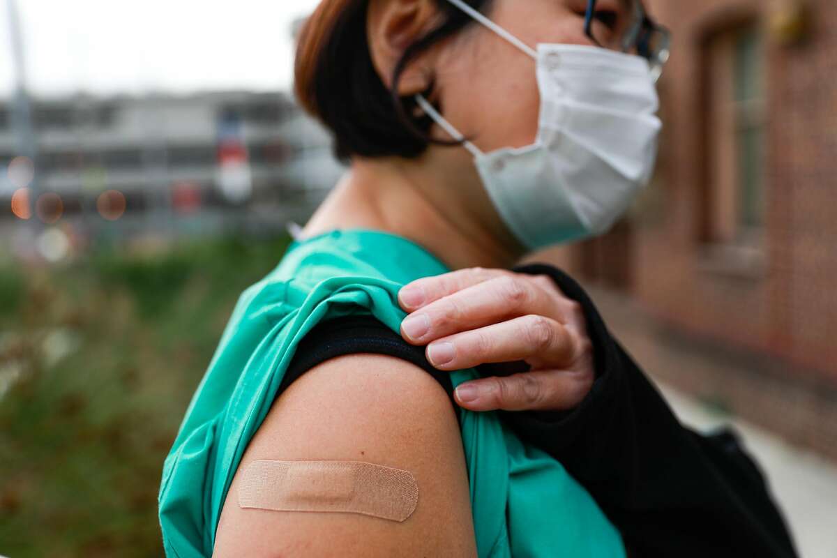 Nurse Phung Nguyen, who works on a COVID-19 floor, shows where she received the COVID-19 vaccine at S.F. General Hospital.