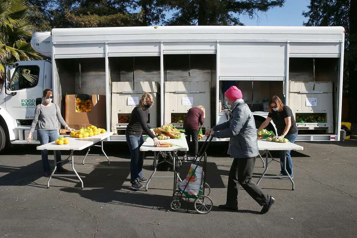 Volunteers for the Food Bank of Contra Costa and Solano distribute fresh produce to clients at Church of the Nazarene in Concord, Calif. on Wednesday, Dec. 2, 2020.