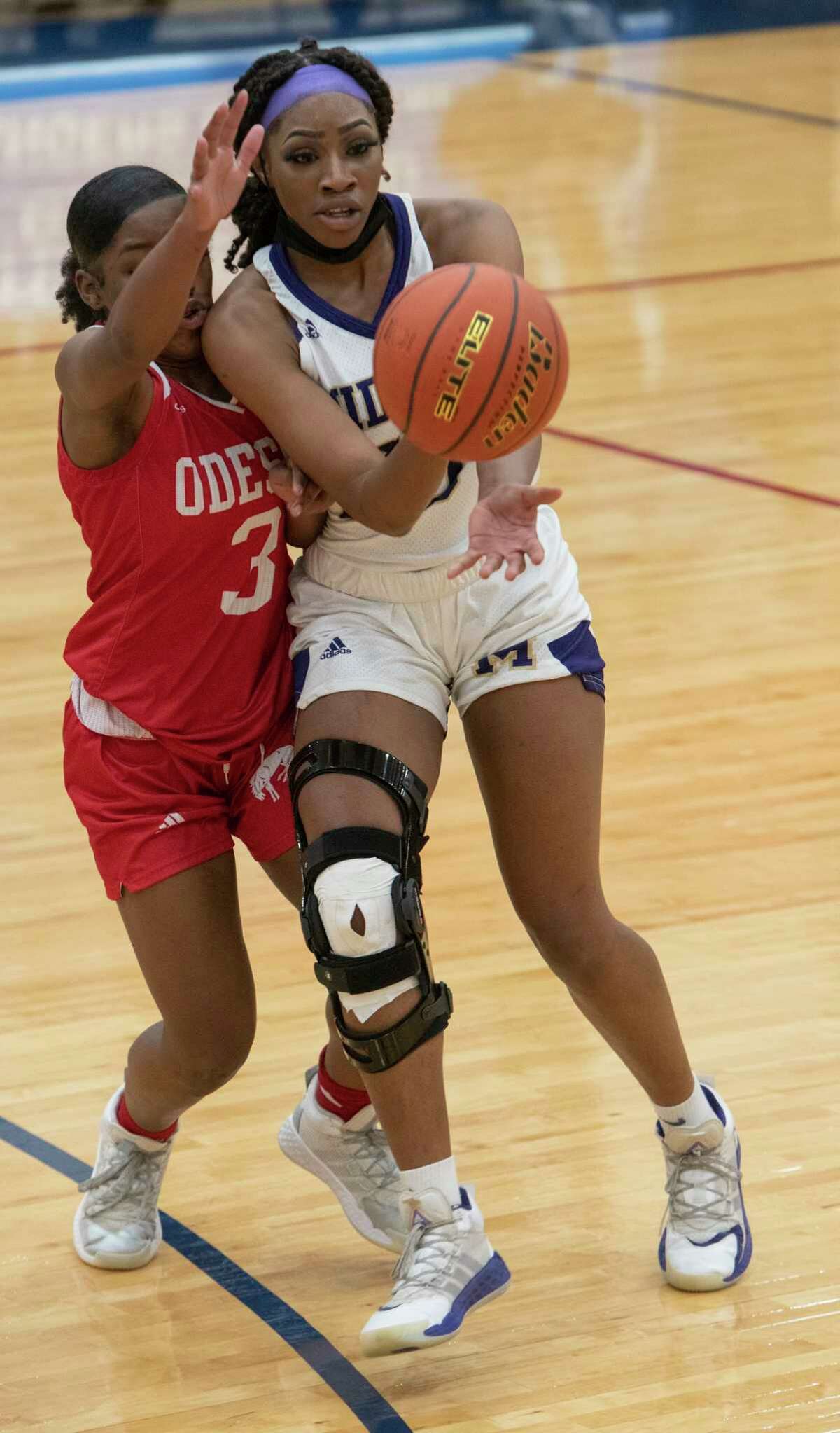 Midland High's Sam Braudaway tries to split Odessa High's Nesha Stephens, 3, and Paige Byford to drive the lane 12/15/2020 at the Odessa High gym. Tim Fischer/Reporter-Telegram