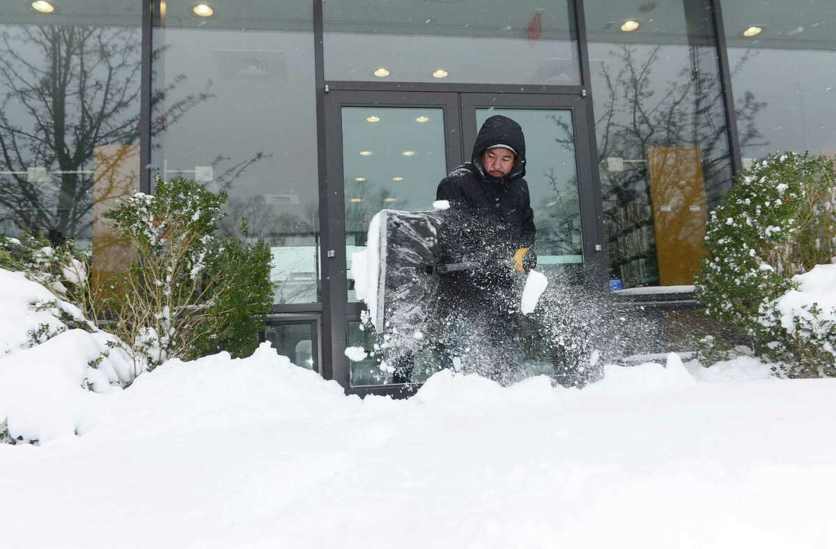 Wilton library employee Juan Carlos Olivares shovels snow from in front of the library during a previous snowstorm. The library is closing at 4 p.m. on Dec. 16 due to a coming storm.