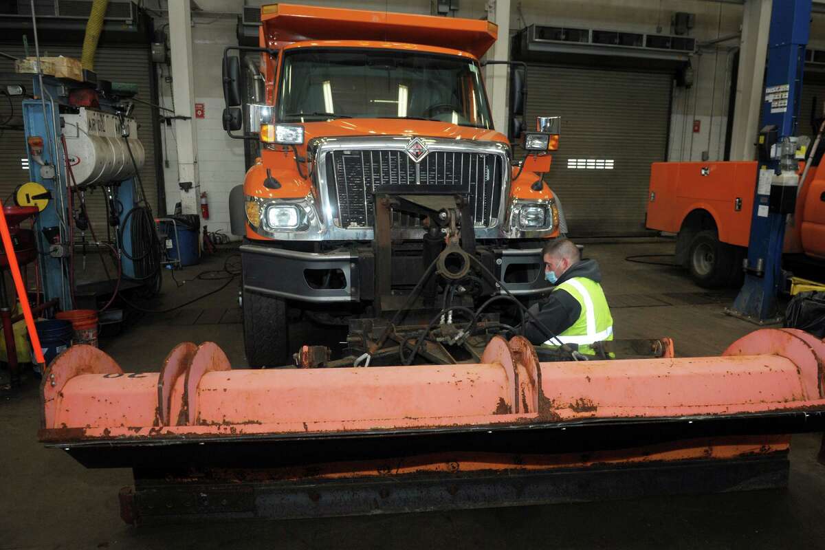 A mechanic works on the snowplow of a truck in the Town of Fairfield’s department of public works garage, in Fairfield, Conn. Dec. 16, 2020.