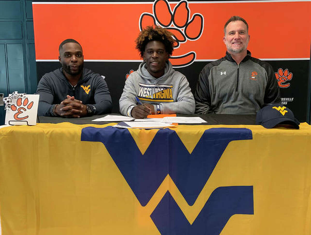 Edwardsville senior Justin Johnson, seated center, will play college football for West Virginia University. He is joined in the picture by his dad, left, and EHS coach Matt Martin.