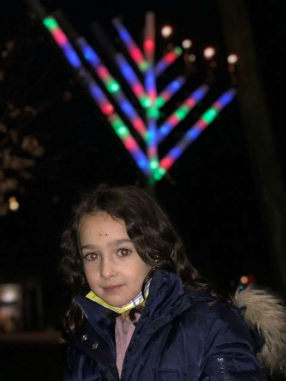 Chaya Deitsch at the menorah lighting presided over by her father, Rabbi Shalom Deitsch of Chabad Jewish Center of Ridgefield. The menorah, visible behind her, had four candles lit on Sunday, the fourth day of Chanukah.