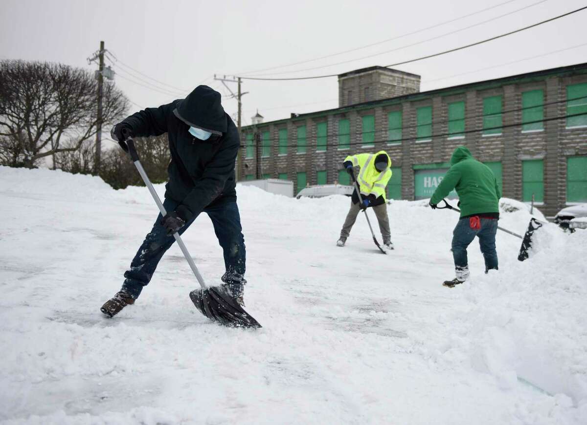 Harrison Cajas, left, and others shovel a driveway in the Byram section of Greenwich, Conn. Thursday, Dec. 17, 2020. The area received more than half a foot of snow starting Wednesday night and continuing into the early morning hours.