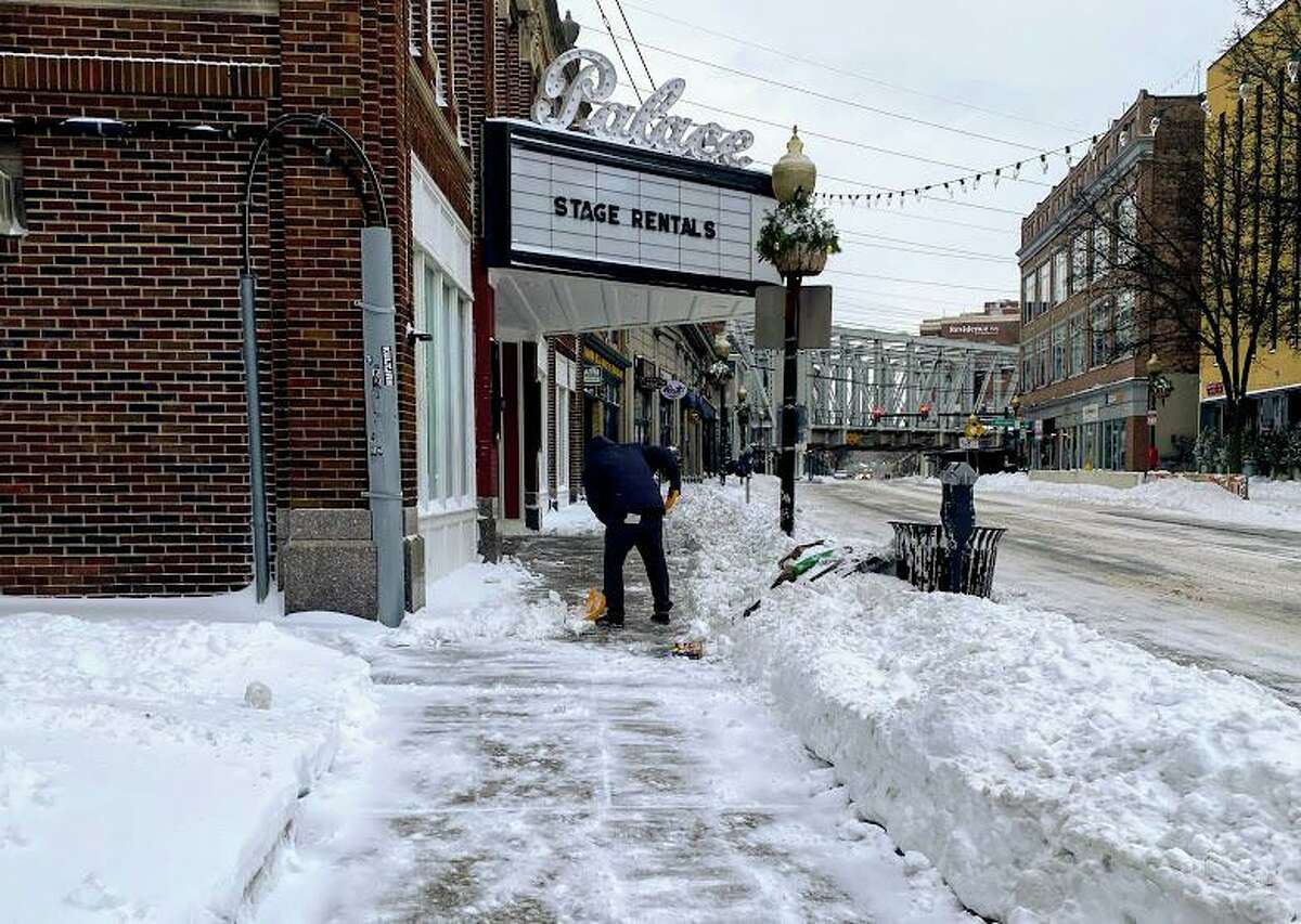 A man shovels the sidewalk outside the Palace Theater in Norwalk, Conn. on Dec. 17, 2020 after a storm brought over 5 inches of snow to the area.