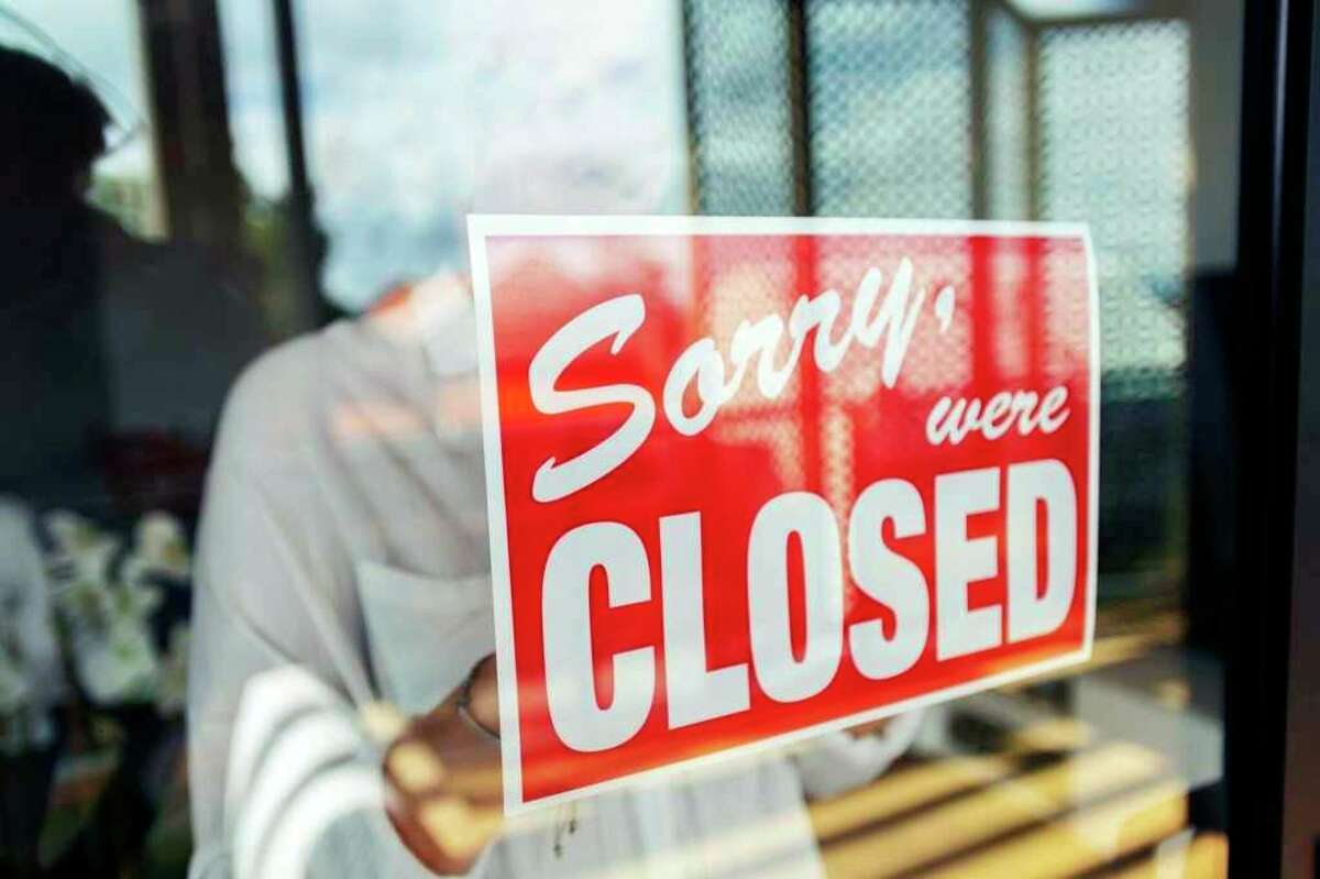 A store owner is pictured putting up a closed sign in the window. (Photo courtesy of Getty Images)