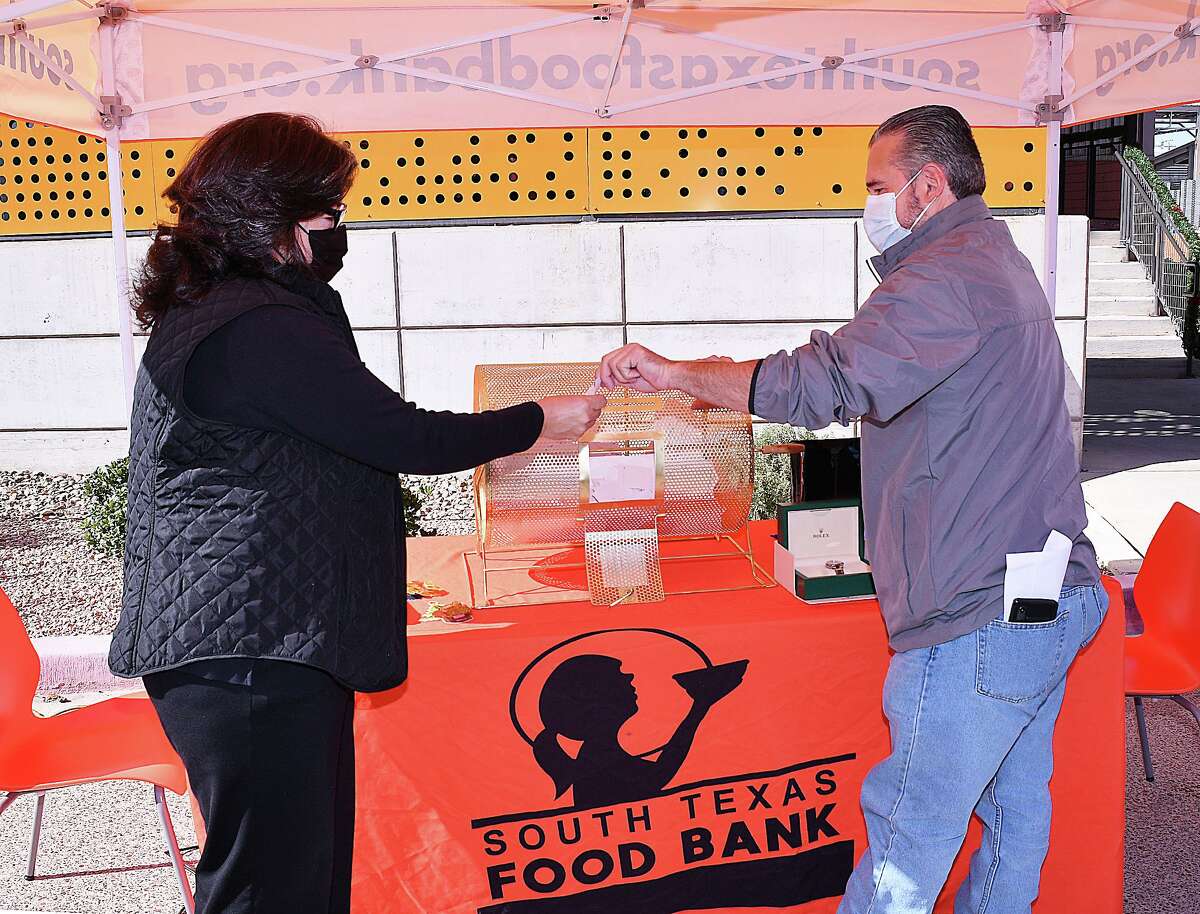 Ruben Villarreal hands the first ticket drawn for the First Virtual Fundraiser:Hunger Relief Holiday Raffle, to South Texas Food Bank Executive Director, Alma Boubel, Wednesday, December 16, 2020. Jessica Leal was the winner of the top prize for the event, a 2020 Mercedes-Benz.