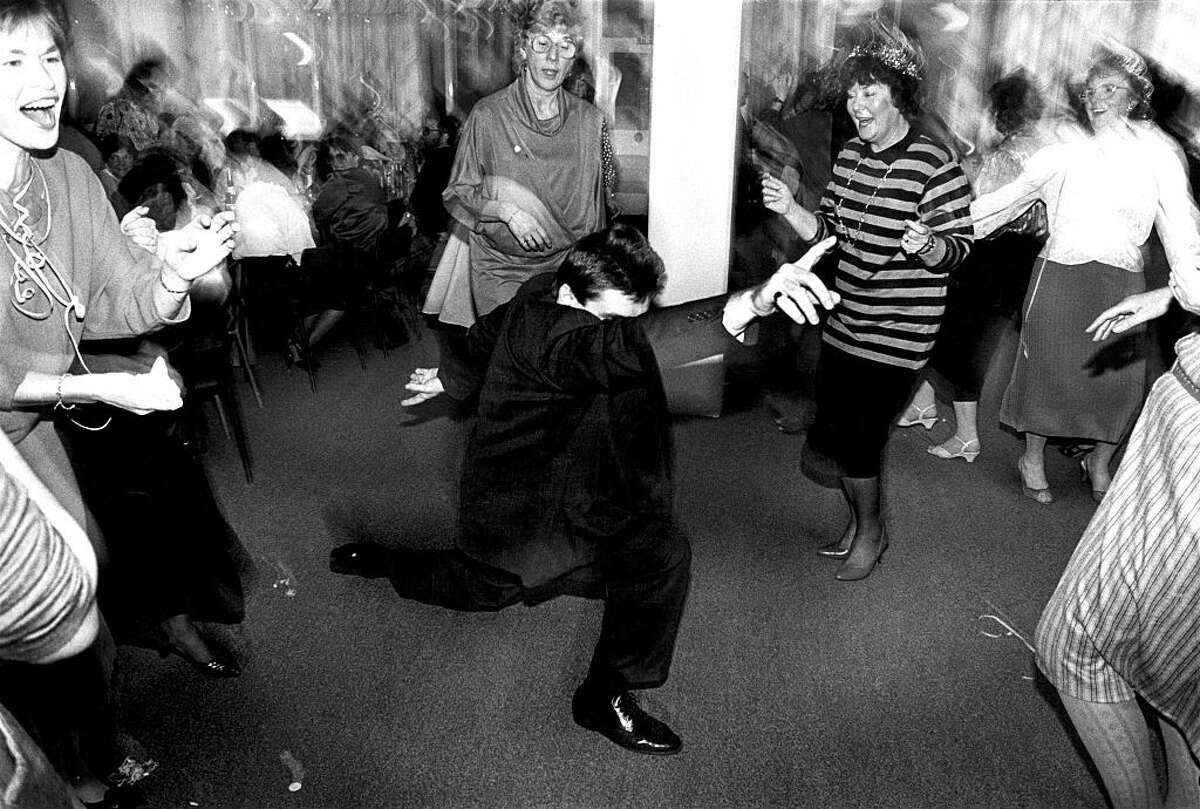 A man strikes a pose dancing in the middle of a group of older women at an office Christmas party in Newport, Wales, around 1990.