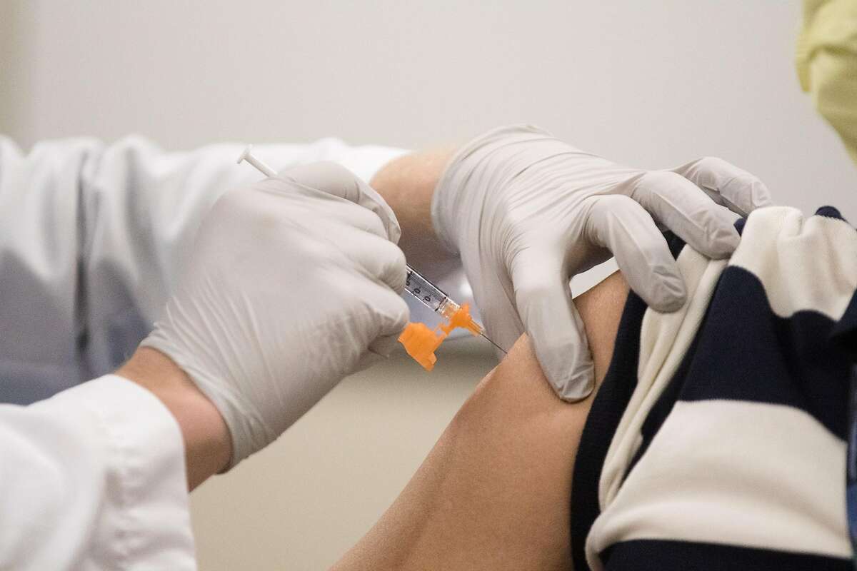 Nurse Kaiser Scott Keech (left) injects one of the first ten Pfizer COVID-19 coronavirus vaccines to hospital frontline worker Derek Chang at Kaiser Hospital in San Francisco on December 17, 2020.