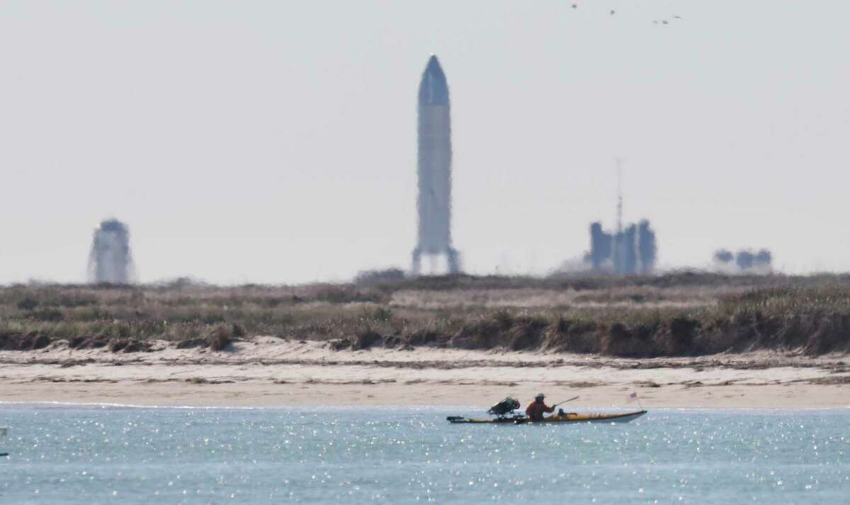 A kayaker is seen from Isla Blanca Park on South Padre Island. Many space enthusiasts from all over the country converged on the Texas beach town where just around 5 miles away stands SpaceX‘s Starship SN8, seen on the horizon before its Dec. 9 launch.