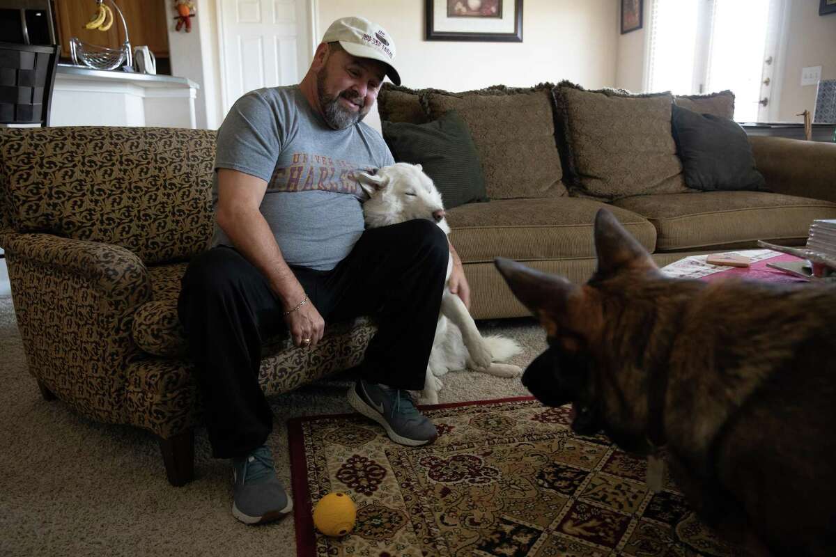 Ivy Jay Arroyo plays with his dogs Odin, left, and Bear, right, at his home in Pflugerville on Nov. 2. He spent weeks hospitalized and on a ventilator at Baylor Scott & White Hospital in Temple with COVID-19. Arroyo was transferred by ambulance after his discharge to a rehab facility in Round Rock. While the hospitals were in-network with his insurance, the ambulance was not. He was stuck with a $2,200 bill that was sent to collections.