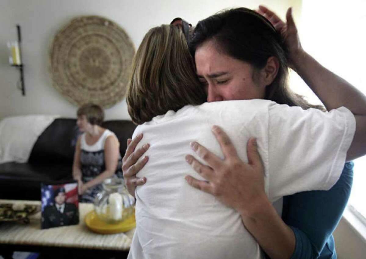 Gabriela Montoya (right), whose brother Diego Montoya was recently killed in action, is comforted by her aunt Liza Balderas of Mission. Rosie Guerra, Diego's mother, sits on the sofa with a portrait of her son. Family members of Diego Montoya, a graduate of Taft High School, gather at their home to support each other.