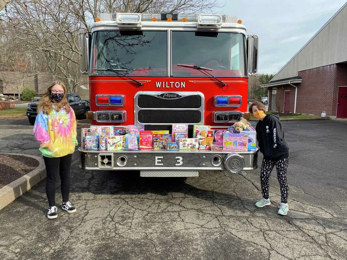 Troop #50798 Cadettes Lucy, left, and Annabelle Shultz with the collection of toy donations dropped off Dec. 13, at the Wilton Fire Department.
