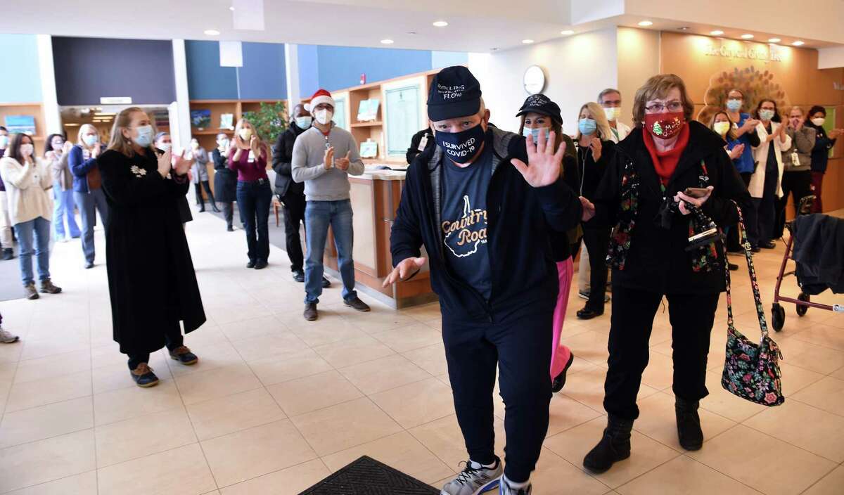 The staff at Gaylord Specialty Healthcare in Wallingford applaud as George Aiello (center) of Bethel leaves after nearly nine months in hospitals recovering from COVID-19 on December 18, 2020. At right is Aiello's wife, Kathleen.George Aiello of Bethel with the assistance of his wife, Kathleen, leaves Gaylord Specialty Healthcare in Wallingford after nearly nine months in hospitals recovering from COVID-19 on December 18, 2020.