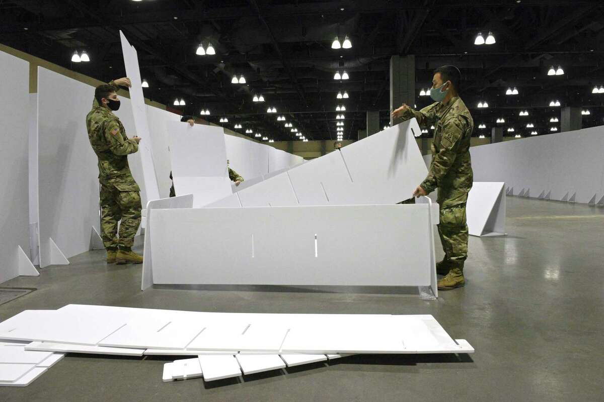 Pvt. Carter Ouellette, of Trumbull, left, and Spc Jonathan Kang, of Rocky Hill, assemble a bed at the Connecticut Convention Center on Friday. The Connecticut National Guard set up a field hospital in the conventen center. Hartford HealthCare will be operating the site, December 18, 2020, in Hartford, Conn.