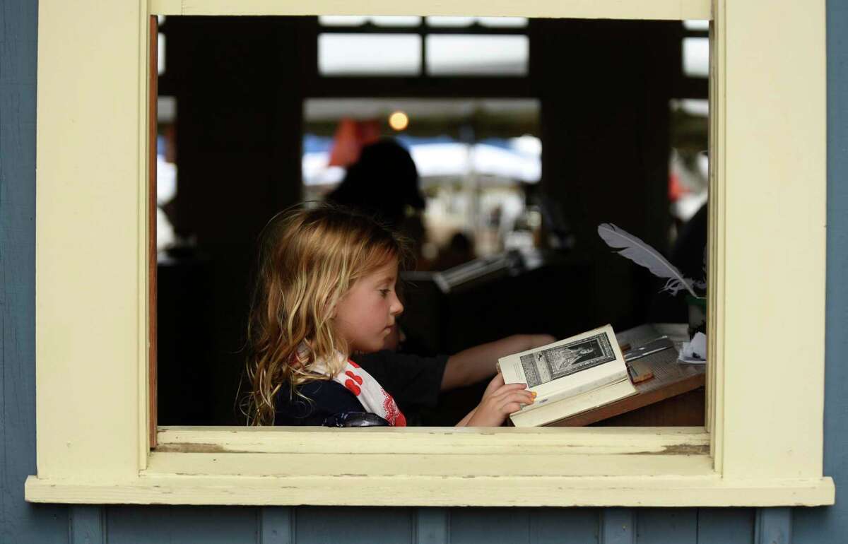 Willa Walter reads through an old book while sitting in a one-room school house during the Texas Folklife Festival on the grounds of the Institute of Texan Cultures.