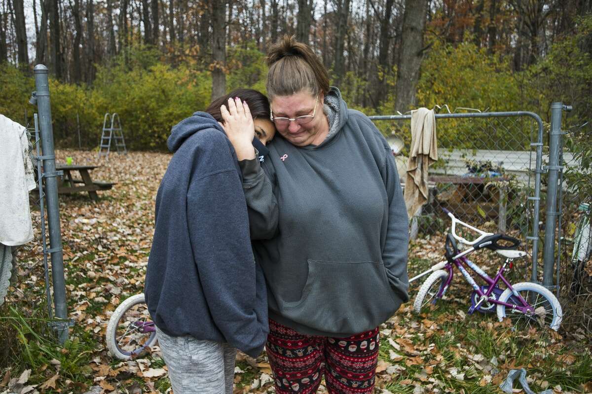 Theresa Ouda, a client of Cancer Services of Midland, right, embraces her daughter, Nuru, 16, left, as Home Depot staff deliver wood pellets and other donated items to the family's home Friday, Oct. 30, 2020. (Katy Kildee/kkildee@mdn.net)