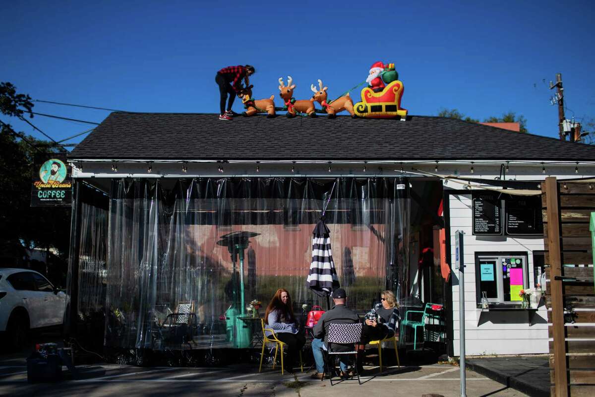 Cora Hendrix, sister of the owner of Uncle Bean’s Coffee, installs Christmas decorations on the roof of the coffee shop in the Heights on Nov. 30.