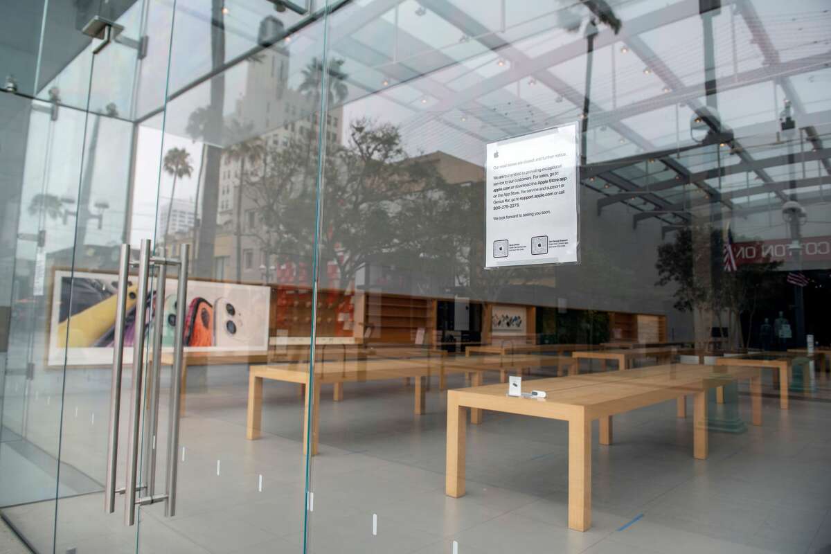 Signs are seen on a window to warn consumers that the Apple Store in Santa Monica, California, was closed on July 28, 2020 amid the coronavirus pandemic.