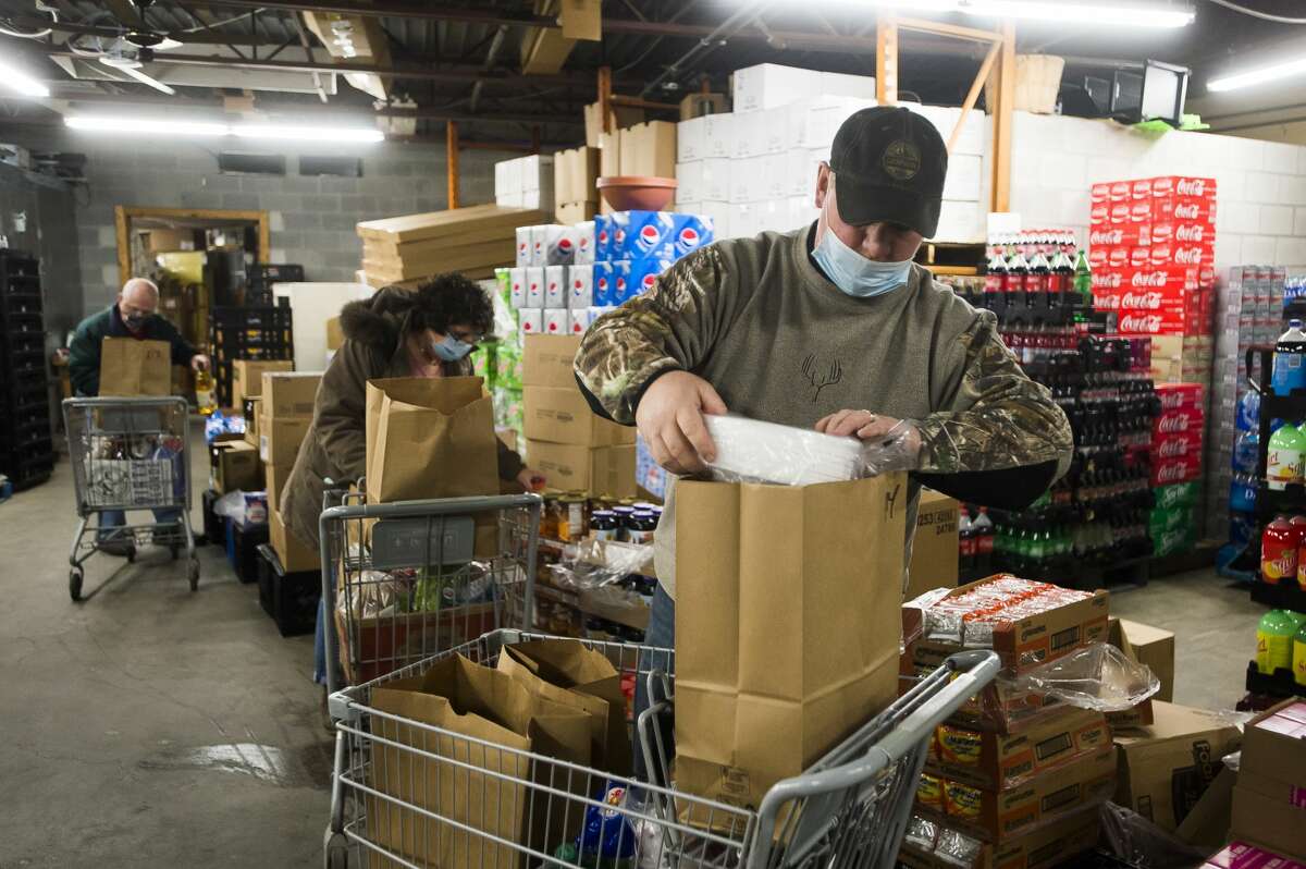 Rob Meyette of Sanford loads groceries into a bag before they are donated to Sanford flood victims through a partnership between The Food Center in Sanford and the Elks Club Friday, Dec. 18, 2020. (Katy Kildee/kkildee@mdn.net)