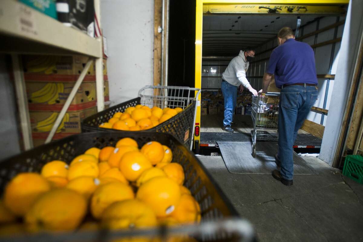 Ed Rodda of Bay City, center, and Ryan Ruszara of Midland, right, load groceries into a truck before they are donated to Sanford flood victims through a partnership between The Food Center in Sanford and the Elks Club Friday, Dec. 18, 2020. (Katy Kildee/kkildee@mdn.net)
