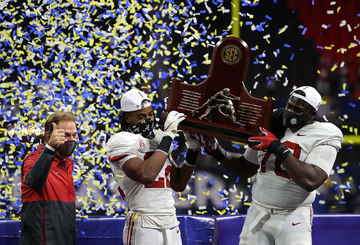 Alabama head coach Nick Saban joins Najee Harris (left) and Alex Leatherwood on the stage following the Crimson Tide’s 52-46 SEC championship game defeat of Florida on Saturday.