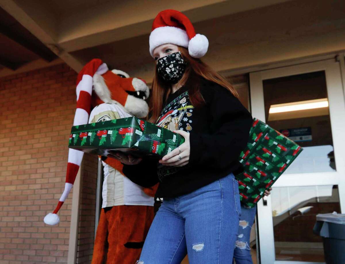 Olivia Westover carries gifts as volunteers and members of Communities in Schools distribute Christmas gifts to students in middle and high school at Conroe High School, Thursday, Dec. 17, 2020, in Conroe.