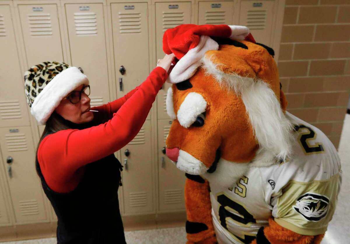 Kelly Miller helps put a festive hat ontop of the Conroe High Schol mascot, Garrett Miller, as volunteers and members of Communities in Schools distribute Christmas gifts to students in middle and high school at Conroe High School, Thursday, Dec. 17, 2020, in Conroe.