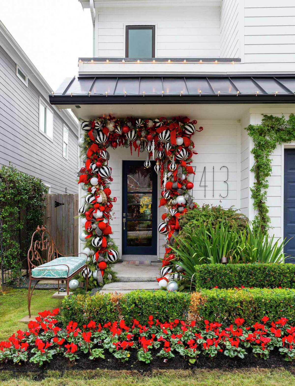 More than 300 bulbs in red or black and white hang on garland around the front door. Red cyclamen in the yard offer complementary holiday color.