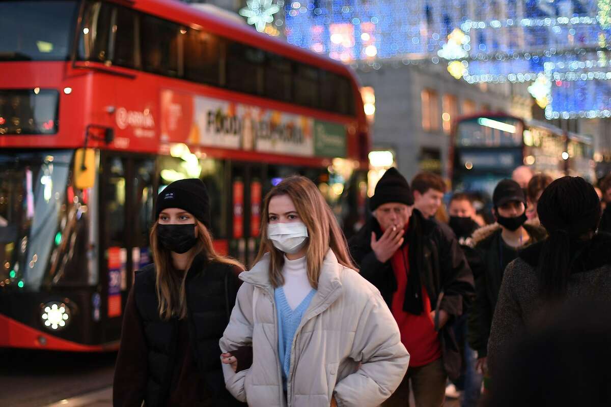 Shoppers, some wearing masks because of the coronavirus pandemic, walk along Regent Street in a London shopping area.