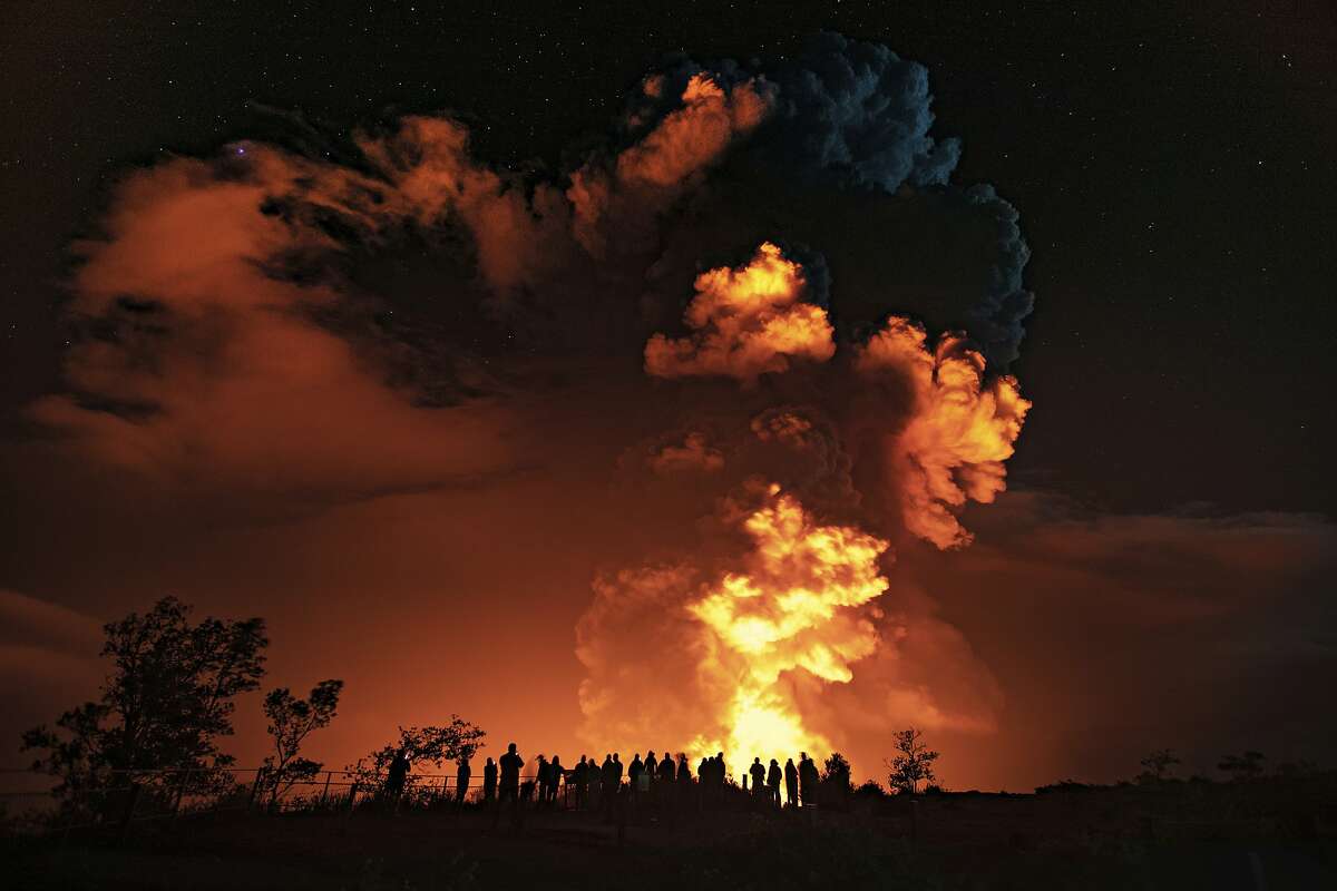 In this photo provided by the National Park Service, people watch an eruption from Hawaii's Kilauea volcano on the Big Island on Sunday, Dec. 20, 2020. The volcano shot steam and an ash cloud into the atmosphere which lasted about an hour, an official with the National Weather Service said early Monday, Dec. 21, 2020. 