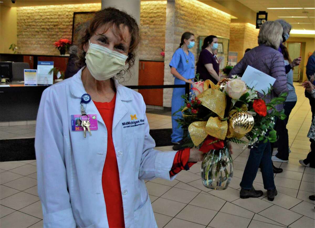 Tonia Vanwieren, nursing director at MidMichigan Health, smiles through her mask as she displays a donated flower arrangement at MidMichigan Medical - Midland on Monday morning, Dec. 21, 2020. Volunteers from the Women of Michigan Action Network (WOMAN) stopped by the Midland hospital to drop off donated gifts, cards, treats and flowers to more than a dozen units of nursing staff for the holidays, amid the coronavirus pandemic. (Ashley Schafer/ashley.schafer@hearstnp.com)
