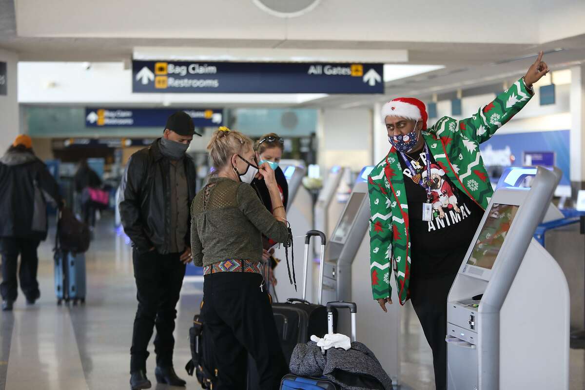 Gail G., left, is aided by a Southwest Airlines employee as she checks in to the Oakland International Airport on Tuesday, December 22, 2020, in Oakland, Calif. (Yalonda M. James / The Chronicle)