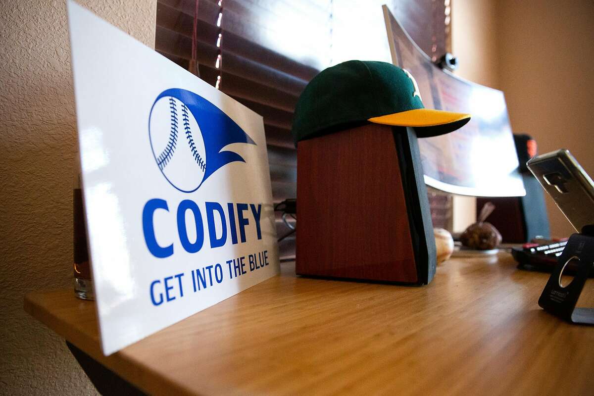 2020年12月15日，在迈克尔·费舍尔位于瓦卡维尔的家庭办公室，Codify公司的标志和奥克兰运动家队和旧金山巨人队的帽子一起放在他的桌子上。