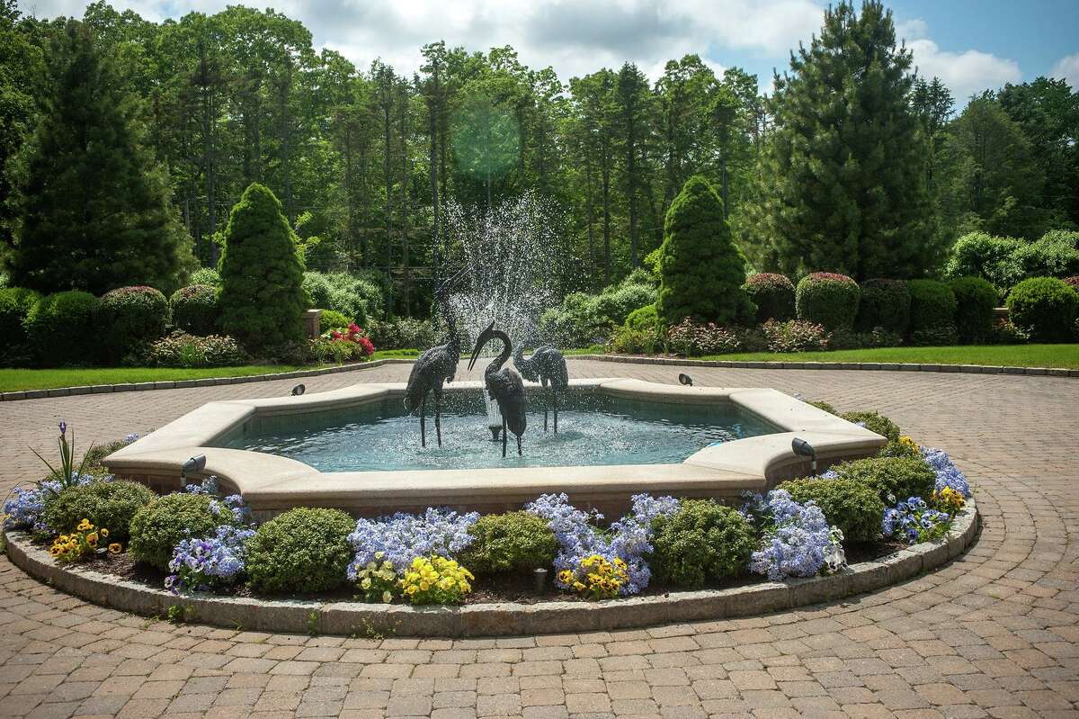 Sculptures of birds frolicking in a fountain sits at the center of the circular courtyard laid out before the main entrance of the 16,765-square-foot house.