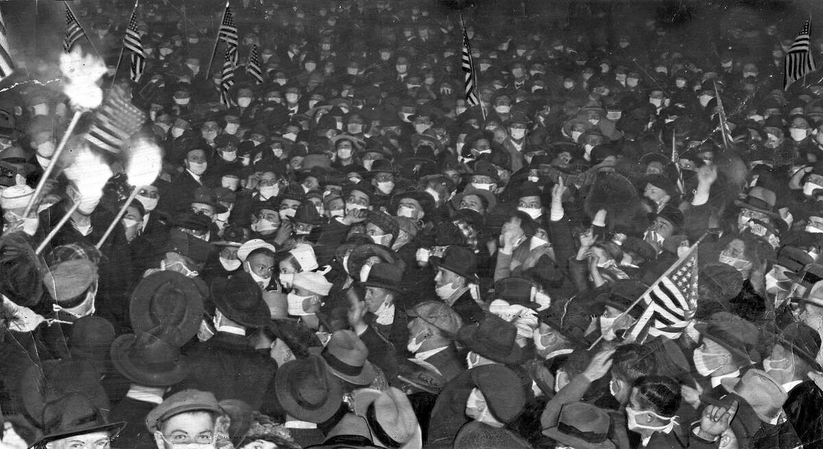 San Francisco residents celebrate the end of World War I on Nov. 11, 1918, with banners and torches and surgical masks.