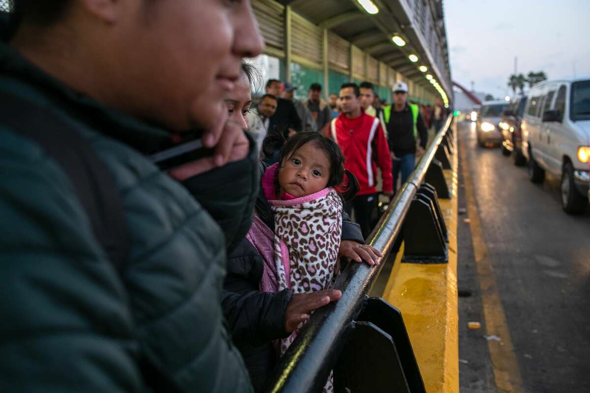A family of Honduran asylum seekers stands on the international bridge from Mexico to the United States on December 09, 2019 in the border town of Matamoros, Mexico. They were waiting to be taken by U.S. officials to an immigration court hearing across the bridge in Brownsville, Texas.