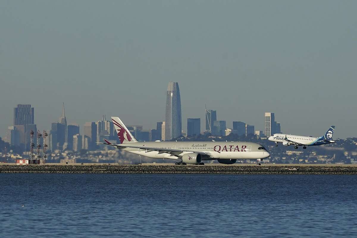 An Alaska Airlines flight lands behind a Qatar Airways plane waiting to take off at SFO on Tuesday. Christmas passenger numbers at the airport are lower than for Thanksgiving.