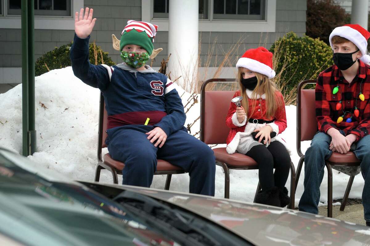 From left, young volunteers Tyler Kudey, Gracie Dumas and Joey Dumas greet seniors during a curbside holiday meal pickup in front the Shelton Senior Center, in Shelton, Conn. Dec. 24, 2020.