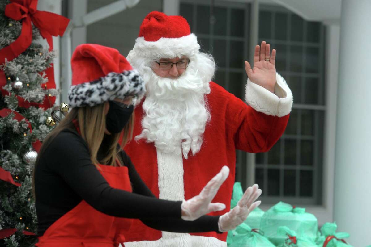 Santa Claus Joe Laucella of Echo Hose Hook, Ladder and Ambulance and Santa’s helper Shauna Dumas, assistant director of the Shelton Senior Center, wave to seniors during a curbside holiday meal pickup in front the center in Shelton, Conn. Dec. 24, 2020.