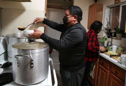 (Left-Right) Roberto Alvarez, (dad), servers posole in the kitchen with Laura Alvarez, (mom), as family prepares for dinner on Christmas Eve at the Alvarez family home in Redwood City, California on Thursday, December 24, 2019. Three out of the four family members recently recovered from Covid-19. Dad Roberto Alvarez remained negative for Covid-19 during his family's illness.