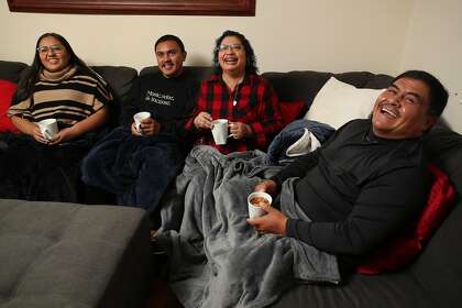 (Left-right) Laura Alvarez, (daughter), Roberto Alvarez, (son Tito), Laura Alvarez, (mom), and Roberto Alvarez, (dad) watch, " A Bad Mom Christmas", movie at their home on Christmas Eve at the Alvarez family home in Redwood City, California on Thursday, December 24, 2019. Three out of the four family members recently recovered from Covid-19. Dad Roberto Alvarez remained negative for Covid-19 during his family's illness.