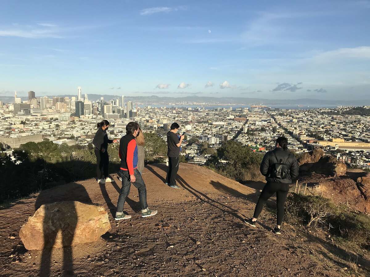 People stare at the area where the gingerbread monolith once stood in Corona Heights Park in San Francisco. Only some icing and crumbs, as well as a small shrine, remained at the site on Saturday.