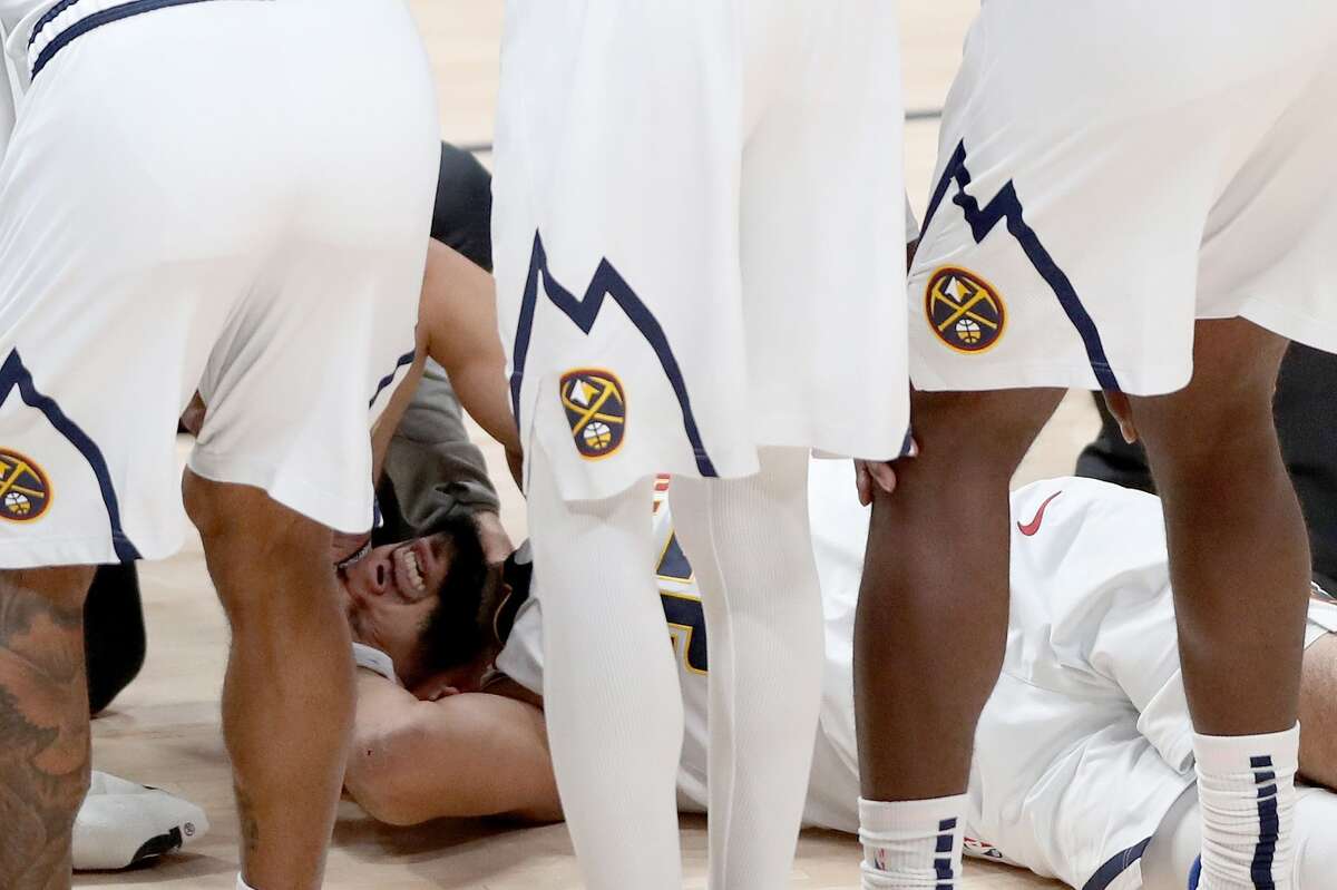 DENVER, COLORADO - DECEMBER 28: Jamal Murray #27 of the Denver Nuggets is attended to after being injured against the Houston Rockets in the third quarter at Ball Arena on December 28, 2020 in Denver, Colorado. NOTE TO USER: User expressly acknowledges and agrees that, by downloading and or using this photograph, User is consenting to the terms and conditions of the Getty Images License Agreement. (Photo by Matthew Stockman/Getty Images)
