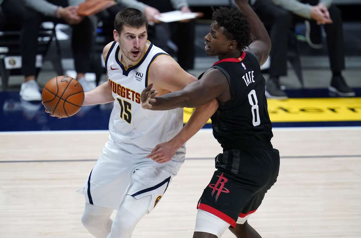Denver Nuggets center Nikola Jokic, left, drives past Houston Rockets forward Jae'Sean Tate in the first half of an NBA basketball game, Monday, Dec. 28, 2020, in Denver. (AP Photo/David Zalubowski)